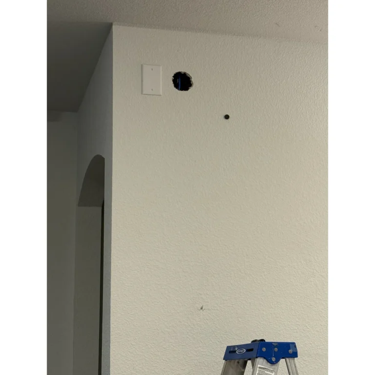 Wall opening prepared for low-voltage wiring during an installation project.