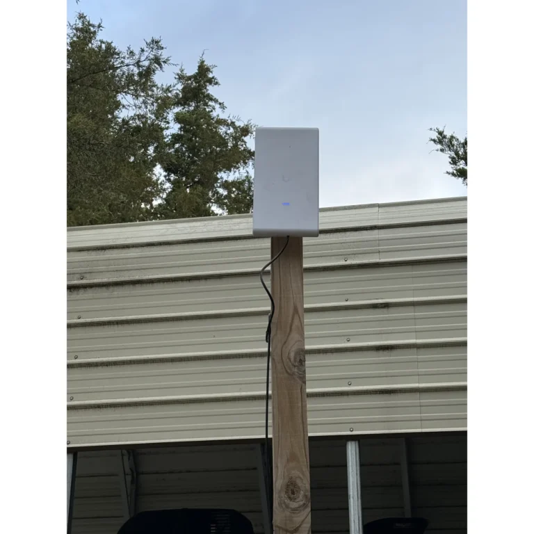 Small exterior network or entry device mounted on a wood post.