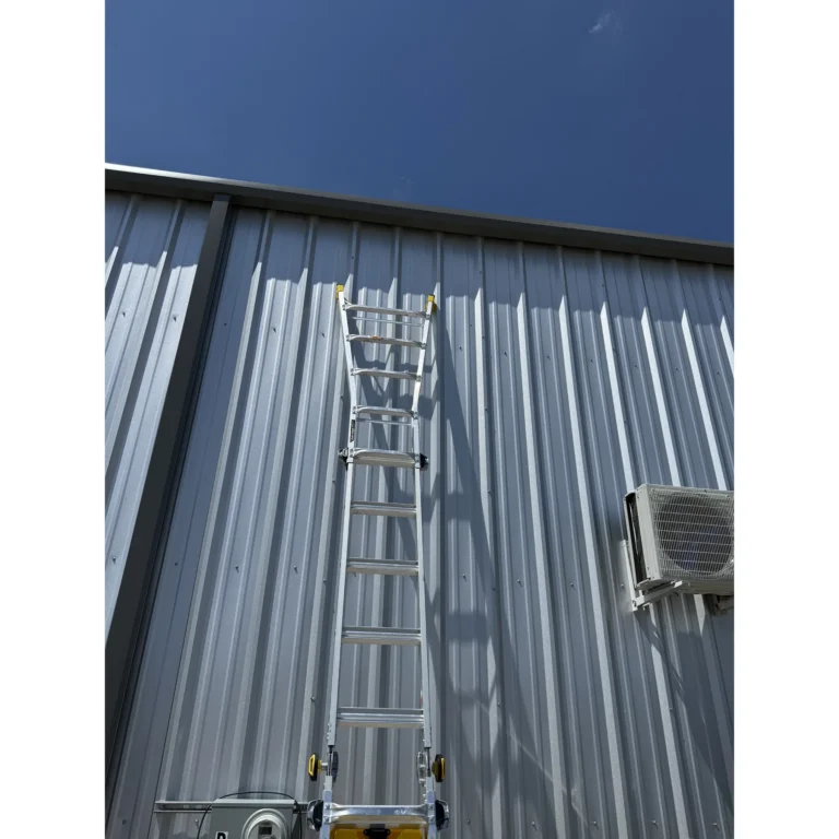 Ladder setup against a metal building for exterior installation work.