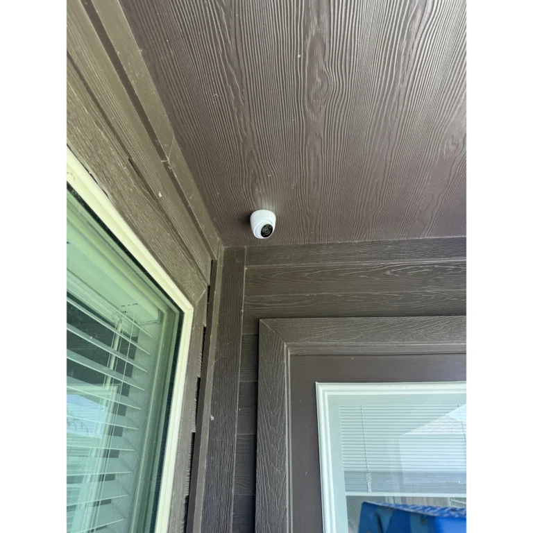 Exterior security camera mounted under a soffit for property coverage and surveillance.